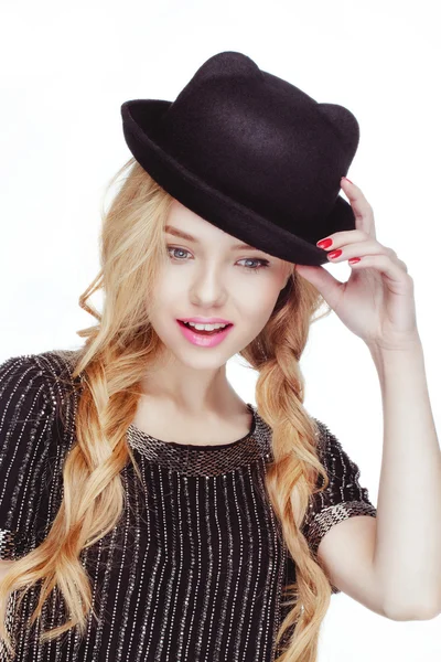 Schöne attraktive junge blonde Frau posiert im Studio weißen Hintergrund in schwarzem Hemd und schwarzem Hut. — Stockfoto
