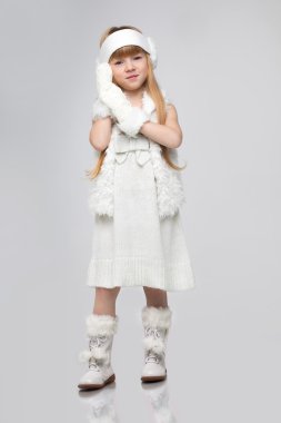 Beautiful little happy redhead girl standing posing in studio white background on total white winter outfit.