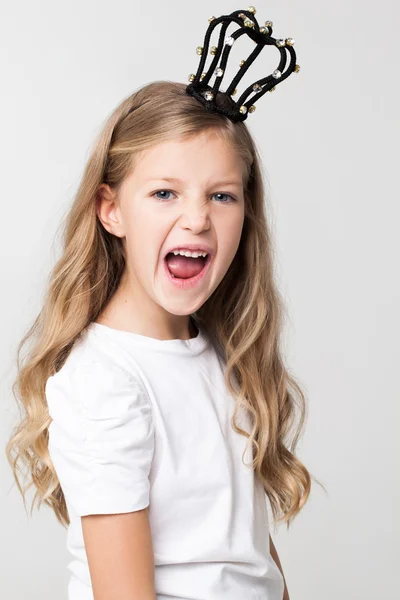 Menina bonita com cabelo loiro vestindo pequena coroa na cabeça, posando no estúdio . — Fotografia de Stock