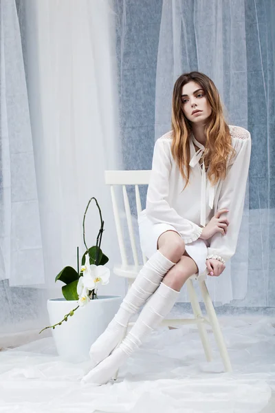 Genç kadın sandalyede oturuyor.