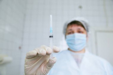 Doktor elinde COVID aşısı olan bir şırınga tutuyor.