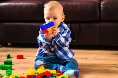 Yerde oturan küçük çocuk tasarımcıyla oynuyor..