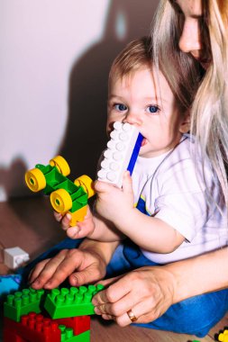 Yerde oturan küçük çocuk tasarımcıyla oynuyor..