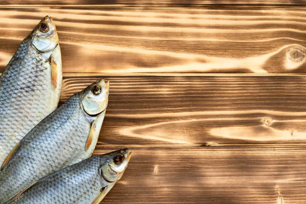 dry fish on a wooden background with space for text