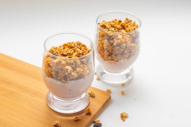 Müsli beyaz arka plan tahtasındaki bir bardakta yoğurt.