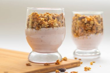 Müsli beyaz arka plan tahtasındaki bir bardakta yoğurt.