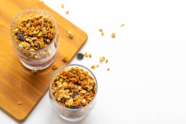 muesli in a glass of breakfast on a white background on a wooden board
