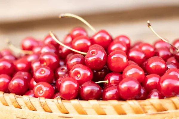ripe sweet red cherry in a basket on a wooden background.