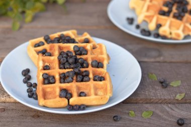 Böğürtlenli Belçika waffleları ahşap arka planda bir tabakta.