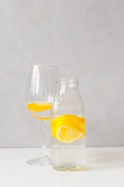 Cam şişe ve arkaplanda su ve limon olan cam kadeh.