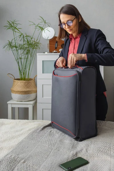 Feliz europeo Millennial mujer de negocios está empacando para el camino, haciendo su maleta para un viaje de negocios o de estudio — Foto de Stock