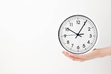 Saat, beyaz ok saati beyaz arka plan kadınlarının elinde siyah oklarla yuvarlak bir saat.