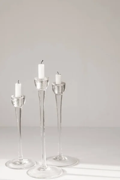 Белые свечи в стеклянных подсвечниках на белом фоне, дизайн интерьера или декор — стоковое фото