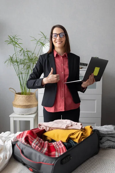 Feliz europeo Millennial mujer de negocios está empacando para el camino, haciendo su maleta para un viaje de negocios o de estudio — Foto de Stock