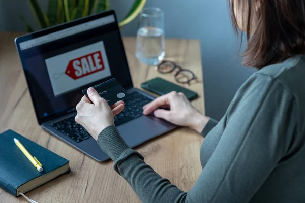 caucasian woman in home office works and pays online, internet surfing shopping online.