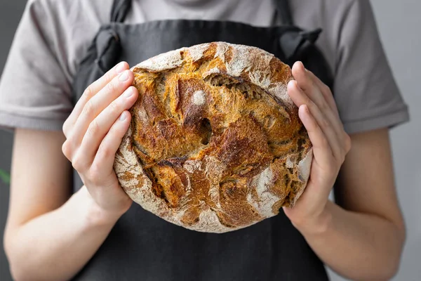 Beyaz kadın fırından taze ekmek çıkarıyor, ev yapımı ekmek pişiriyor.