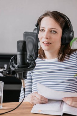 podcast, audio content creation. a beautiful European woman podcaster or radio host records a podcast or content in a recording studio