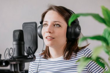 podcast, audio content creation. a beautiful European woman podcaster or radio host records a podcast or content in a recording studio