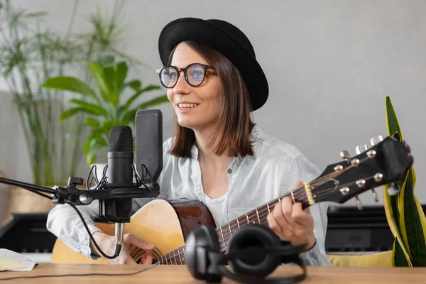 Podcast, creación de contenido de audio musical. hermosa mujer europea podcaster en un sombrero con una guitarra o ukelele, radio anfitrión grabación podcast o contenido, canción y música en un estudio de grabación — Foto de Stock
