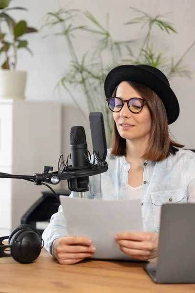 beautiful european woman podcaster with headphones and microphone records podcast in recording studio