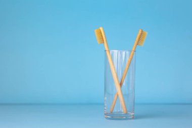 Bardakta mavi bir arka planda bambu diş fırçaları. Cinsi önemseyen insanlar için çevre dostu kişisel bakım ürünleri.