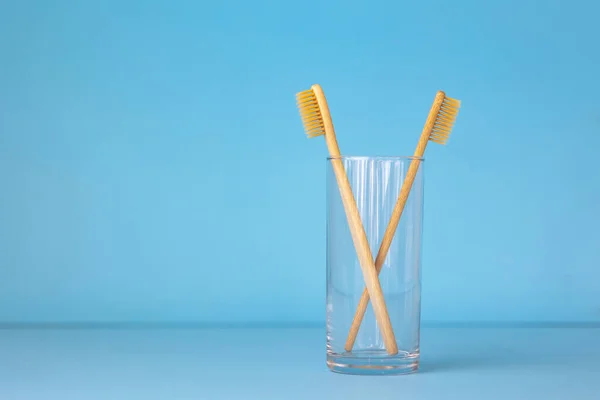 Escovas de dentes de bambu em um fundo azul em um vidro, produtos de cuidados pessoais eco-friendly para pessoas que se preocupam com a raça — Fotografia de Stock