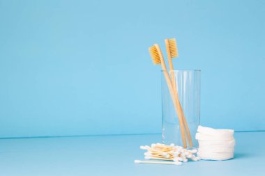 Bardakta mavi bir arka planda bambu diş fırçaları. Cinsi önemseyen insanlar için çevre dostu kişisel bakım ürünleri.
