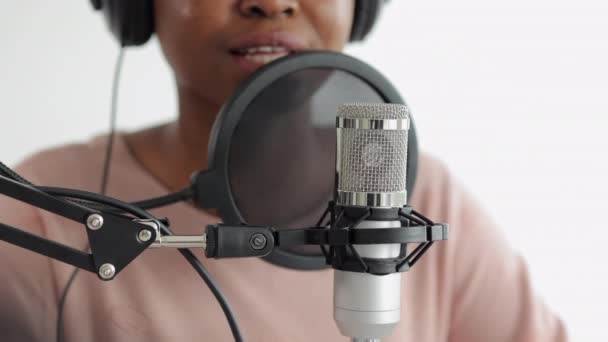 Podcast and audio content creation, confident and beautiful African-American woman with a microphone and headphones recording a podcast in a recording studio or in her home — Stock Video