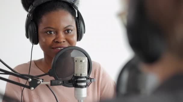 Evropská žena se sluchátky mluví do mikrofonu, dvě ženy v nahrávacím studiu vytvářejí audio obsah — Stock video