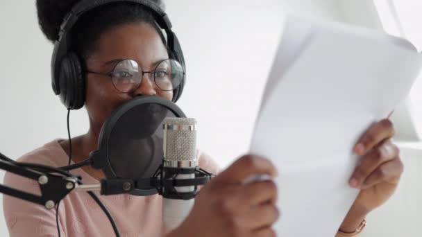 A confident and beautiful African-American woman with a microphone and headphones reads text, — Stock Video