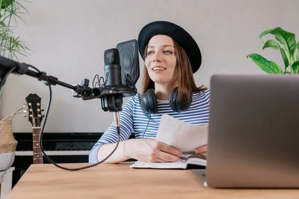beautiful european woman podcaster with headphones and microphone records podcast in recording studio