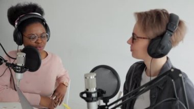 İki kadın bir kayıt stüdyosunda ses içeriği yaratıyor, bir podcast veya radyo programı kaydediyor