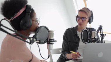 İki kadın bir kayıt stüdyosunda ses içeriği yaratıyor, bir podcast veya radyo programı kaydediyor