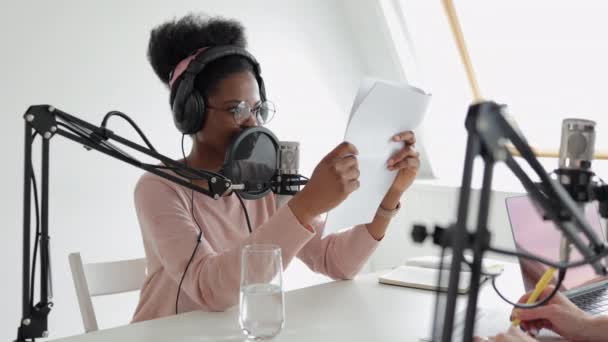 Une femme afro-américaine confiante et belle avec un microphone et un casque lit du texte, — Video