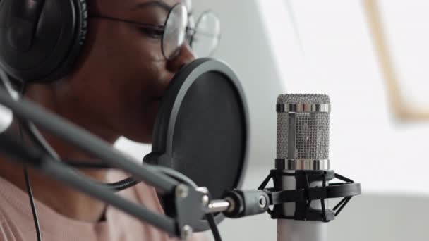 Création de podcasts et de contenus audio, femme afro-américaine confiante et belle avec microphone et écouteurs enregistrant un podcast dans un studio d'enregistrement ou chez elle — Video