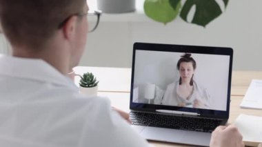 Teletıp, muayenehanesinde beyaz önlüklü bir doktor bir hastayla internet üzerinden iletişim kuruyor.