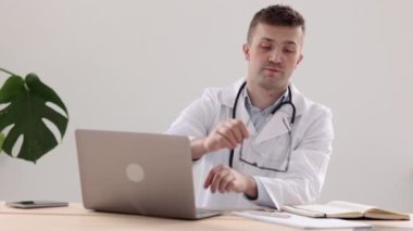 Teletıp, beyaz önlüklü ve gözlüklü Avrupalı bir doktor bir günlük ve defter girişine not alır.