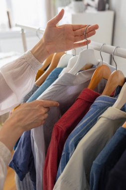 Bir kadının eli askıda, korkulukta ya da salonda giysileri tutan bir kadın.