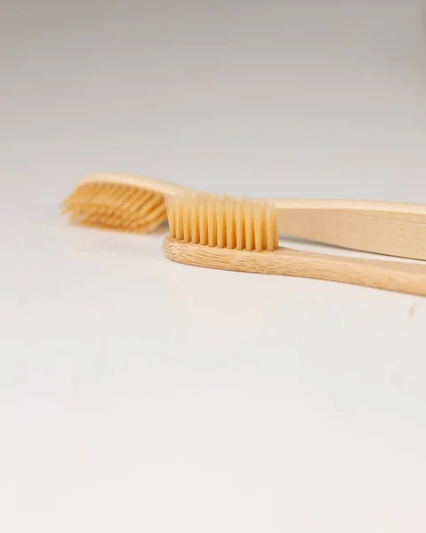 Daily human hygiene, cotton swabs and cotton pads, a womans hand holding bamboo toothbrushes on a light background in a glass or against the background of a wooden tray — Stock Photo, Image