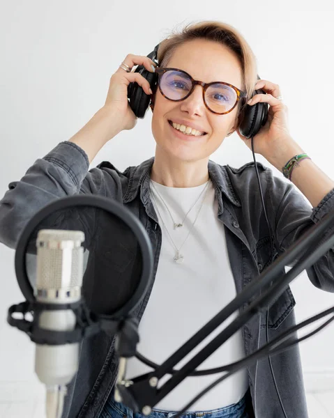 Young and confident European woman recording a podcast in a recording studio