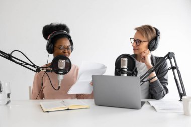 Podcaster 'lar, Afrikalı Amerikalı ve Avrupalı kadın kulaklıklar ve mikrofonlar