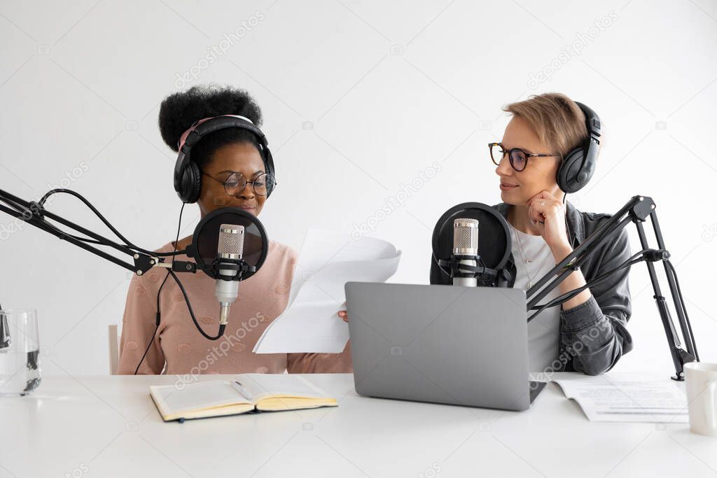 Podcasters, African American and European woman with headphones and microphone