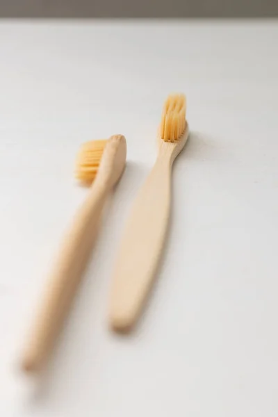 Daily human hygiene, cotton swabs and cotton pads, a womans hand holding bamboo toothbrushes on a light background in a glass or against the background of a wooden tray — Stock Photo, Image