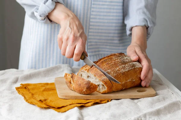 Las manos de las mujeres sostienen el pan contra el fondo de un delantal ligero — Foto de Stock