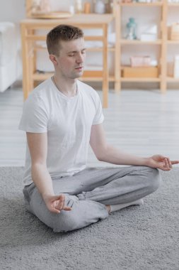 Avrupalı bir adam geniş ve rahat dairesinde, spor veya yogasında meditasyon yapar.,