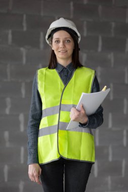 Beyaz kasklı ve çelik yelekli kadın mühendis, şantiyedeki mühendis.