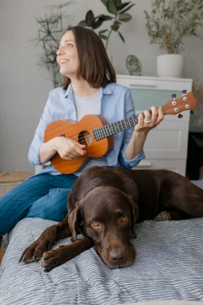 Mujer tocando la guitarra o ukelele con su perro — Foto de Stock