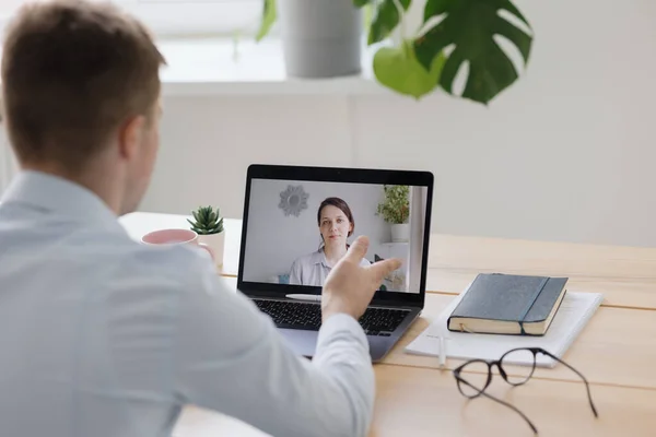 Telemedicina, egy fiatal felnőtt európai és hozzáértő orvos fehér köpenyben egy orvosi klinikán az irodájában lát egy beteget online — Stock Fotó