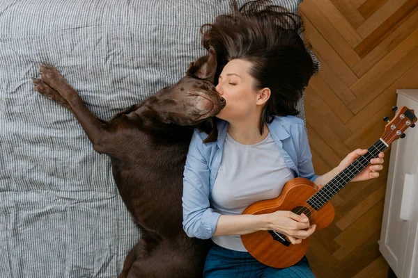 Mujer tocando la guitarra o ukelele con su perro — Foto de Stock