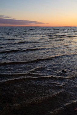 Gölde ya da koyda gün batımı, batan güneşin altında güzel deniz dalgaları.